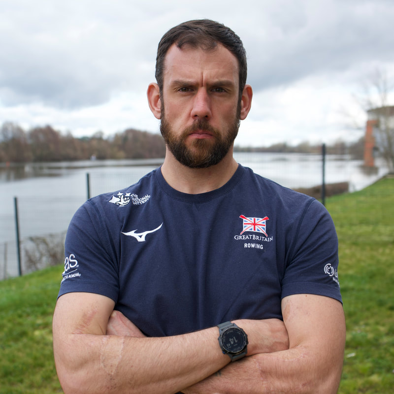 Ben Gallagher wearing Great Britain rowing kit beside the water